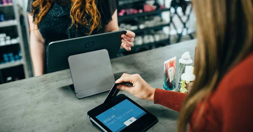 Woman swiping credit card at retail checkout, influenced by customer personas
